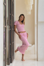 Load image into Gallery viewer, Woman in pink pink shirred top and shirred maxi skirt outfit standing in a doorway.