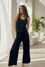 Load image into Gallery viewer, Woman wearing a black sleeveless top and wide-leg pants in a clothing store.
