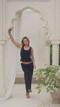 Load and play video in Gallery viewer, Woman wearing a black maxi skirt and tank top in a marble courtyard setting.