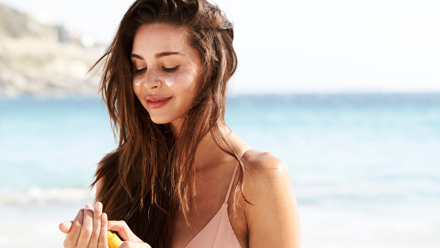 Young Lady applying Sunscreen on her face