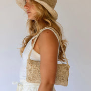 Woman wearing a hemp sun hat and carrying a matching hemp bag against a white background