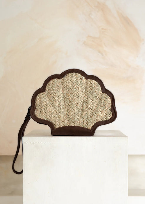 Shell-shaped clutch bag made of woven material on a white pedestal with a neutral background