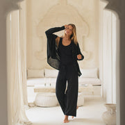 Woman in black outfit standing in a white, ornate room.