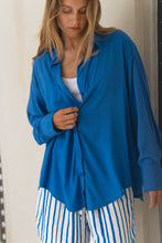 Load image into Gallery viewer, Woman wearing a blue shirt and white striped pants indoors.
