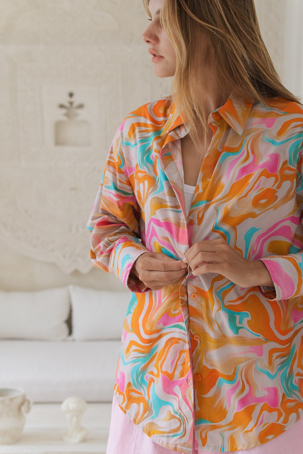 Woman wearing a colorful patterned shirt in a bright room