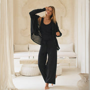 Woman in a black shirt, tank top and pants standing in a luxurious room with white decor