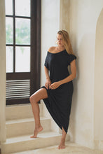Load image into Gallery viewer, Woman in a black maxi dress standing on a staircase in a bright room.
