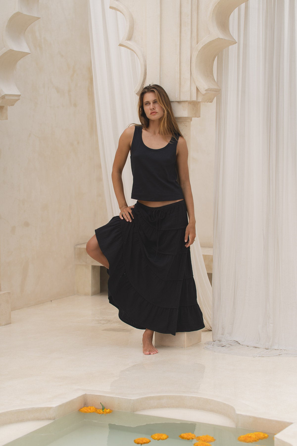 Woman wearing a black skirt and tank top in a marble interior setting