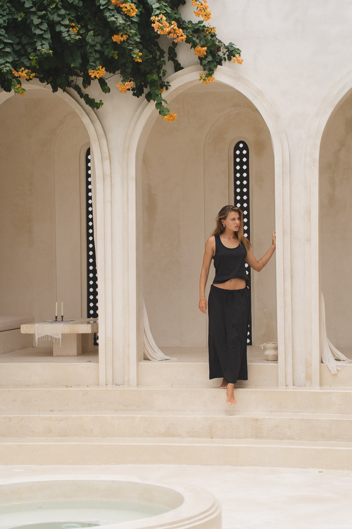 Woman wearing a black maxi skirt and tank top in front of a decorative archway.