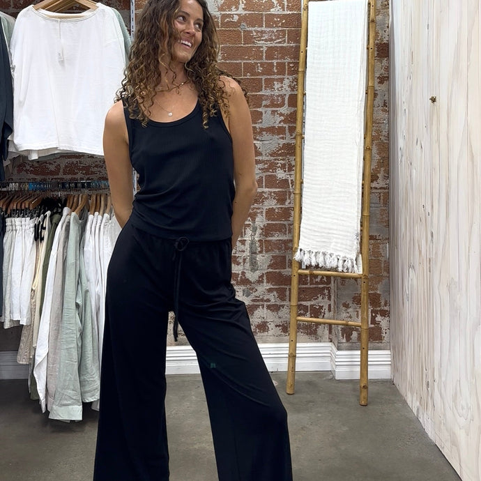 Woman wearing a black sleeveless top and black travel pants in Desert to Ocean clothing store.