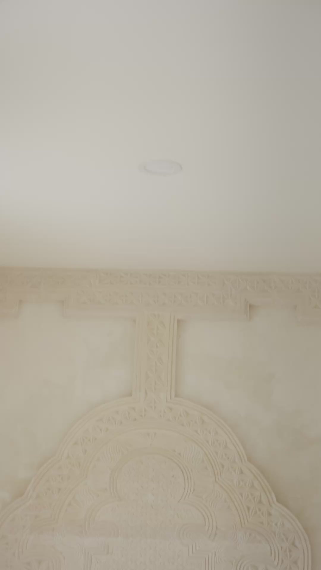 Load video: Woman wearing an orange shirt over a pink top and orange striped pants sitting on a daybed against a white wall.