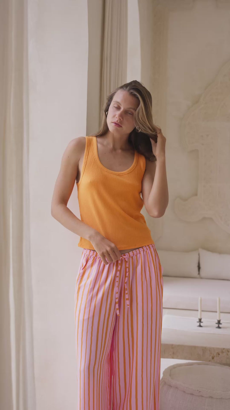 woman wearing orange tank top and striped pants