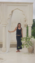 Load and play video in Gallery viewer, Woman in a black tank top and skirt  standing on steps with white columns in the background
