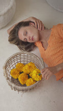 Load and play video in Gallery viewer, Woman in orange shirred top and maxi skirt lying on a daybed with intricate wall designs in the background
