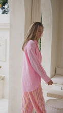 Load and play video in Gallery viewer, Woman wearing a pink shirt over an orange top and striped pants in a neutral setting
