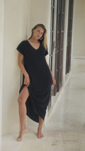 Load and play video in Gallery viewer, Woman in a black maxi dress standing  in a bright room.
