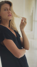 Load and play video in Gallery viewer, Woman in a black maxi dress standing in a bright room.
