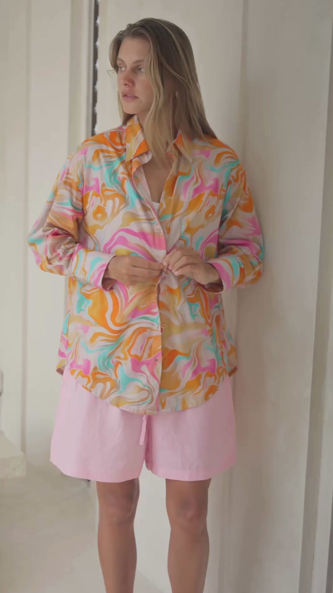 Load video: Woman wearing a colorful patterned shirt in a bright room