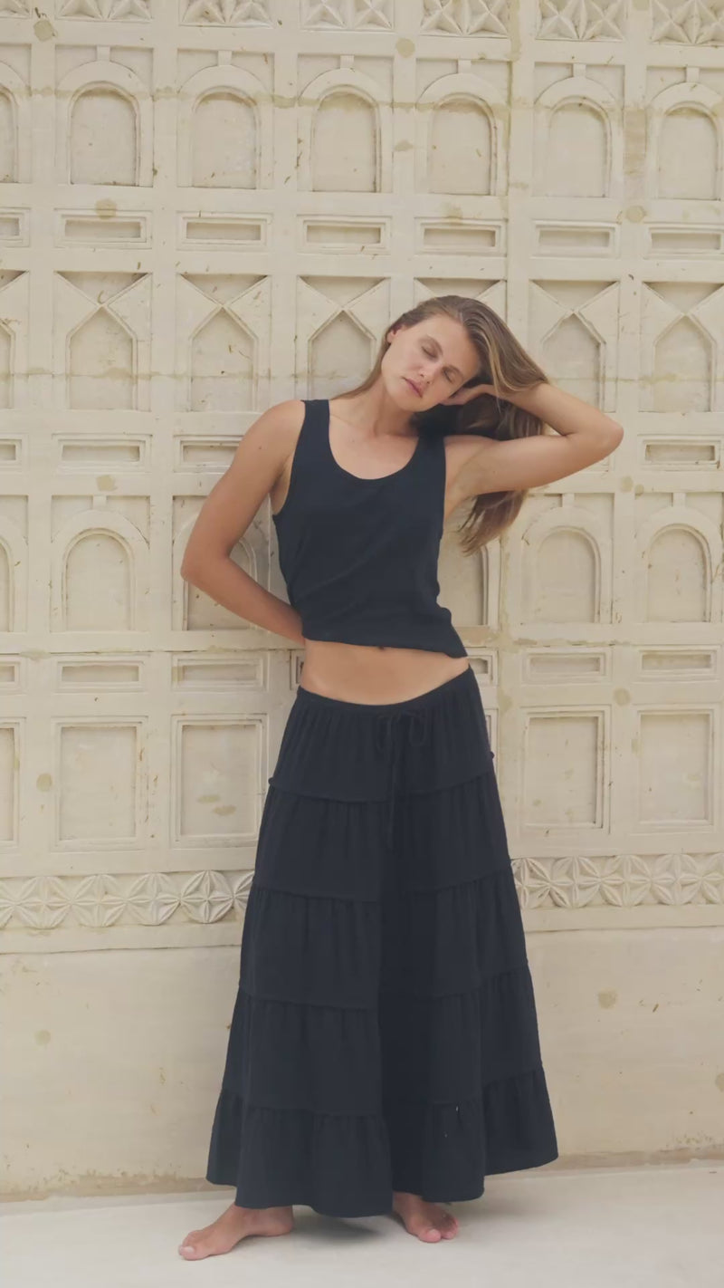 Woman wearing a black tiered skirt and tank top in a marble interior setting