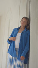 Load and play video in Gallery viewer, Woman standing by an arched doorway wearing a blue shirt, white tank top, and striped paants.
