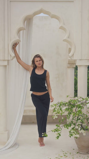 Woman wearing a black maxi skirt and tank top in a marble courtyard setting.