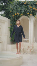 Load and play video in Gallery viewer, Woman in a black shirtdress standing in a spa-like setting
